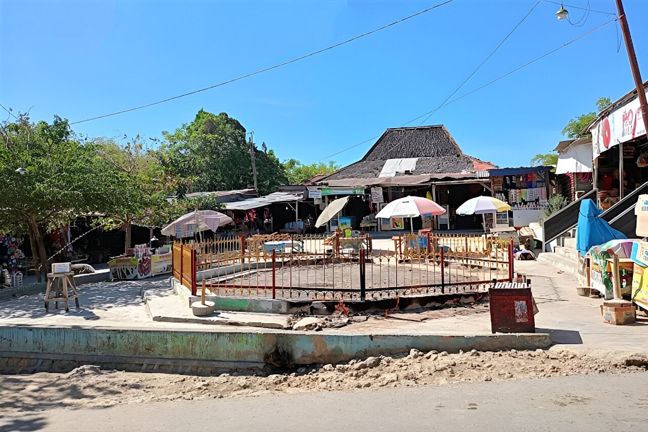Area api abadi pada siang hari, dikelilingi warung dan payung pedagang
