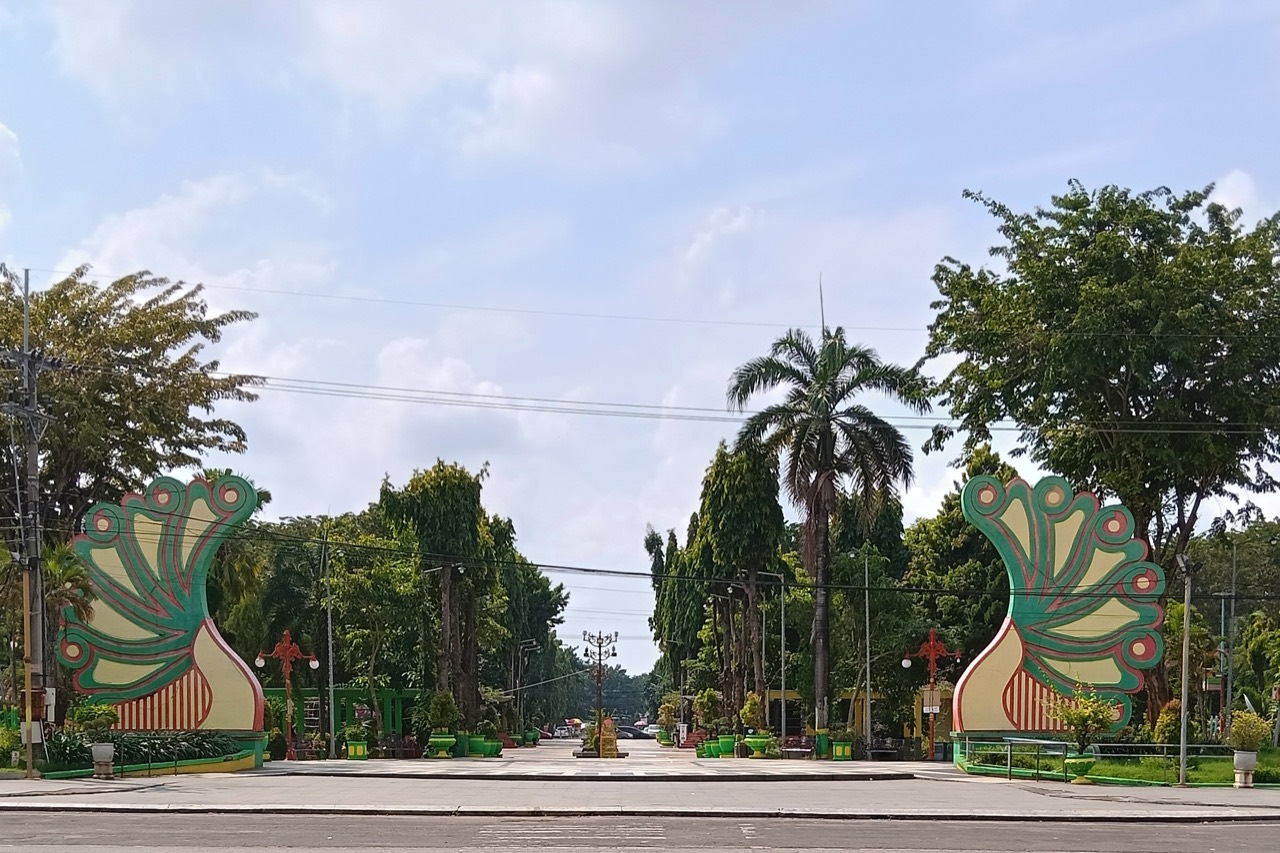 Alun-alun Taman Adipura Sumenep dengan rumput luas dan pohon-pohon di tepinya