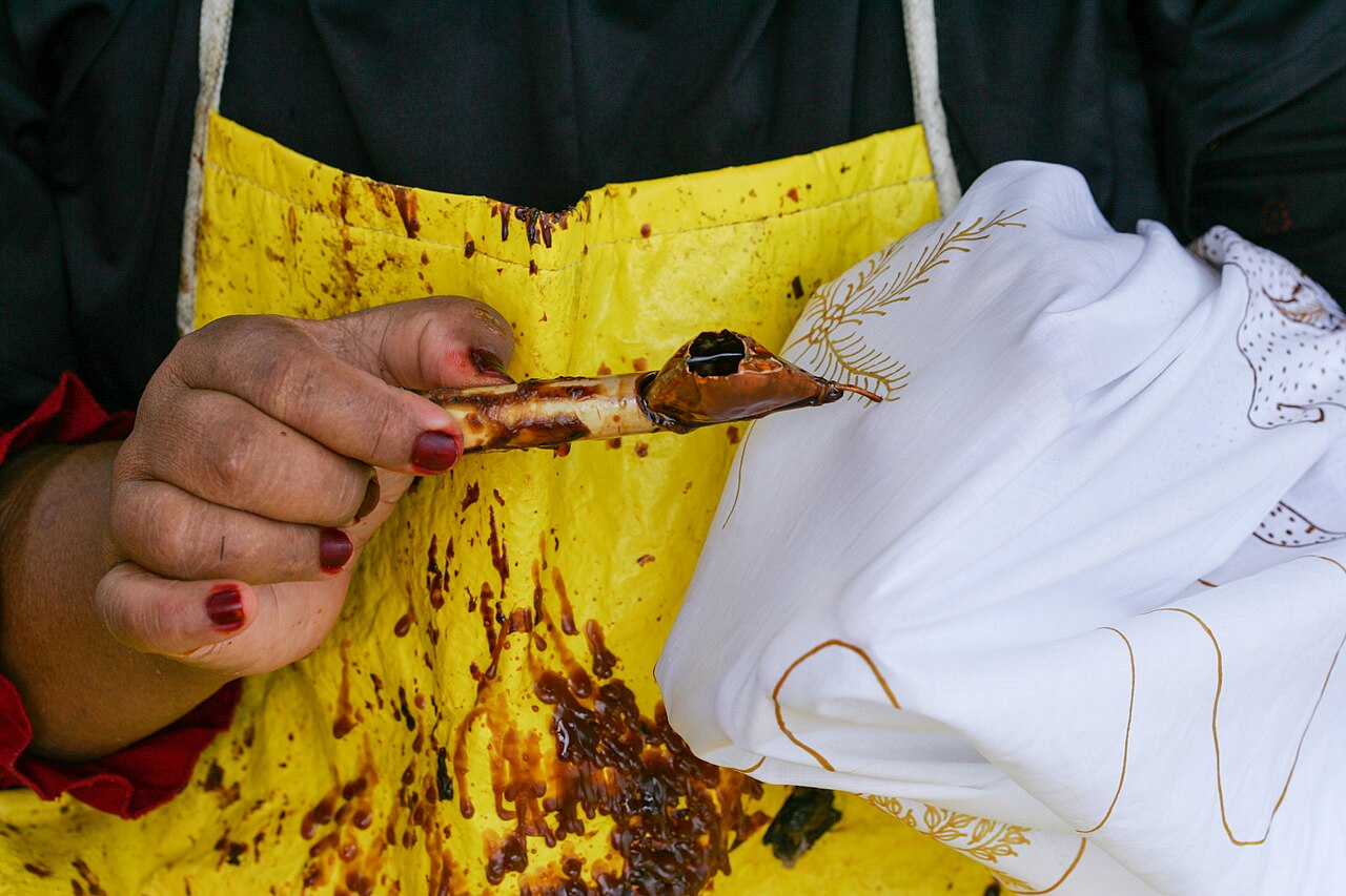 Canting berisi malam cair didekatkan ke kain yang sedang dibatik