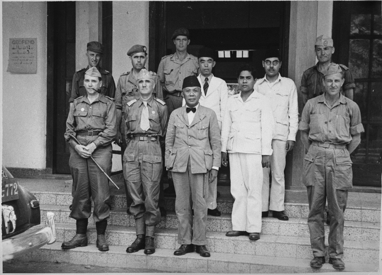 Foto hitam putih Cakraningrat XII berpeci di tangga sebuah gedung, dikelilingi tentara Belanda berseragam