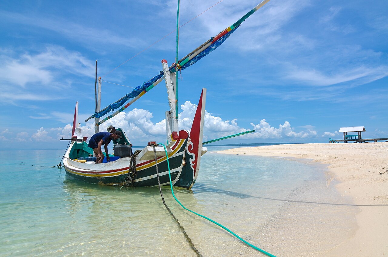 Perahu nelayan tradisional Madura bersandar di air dangkal berwarna toska di Gili Labak