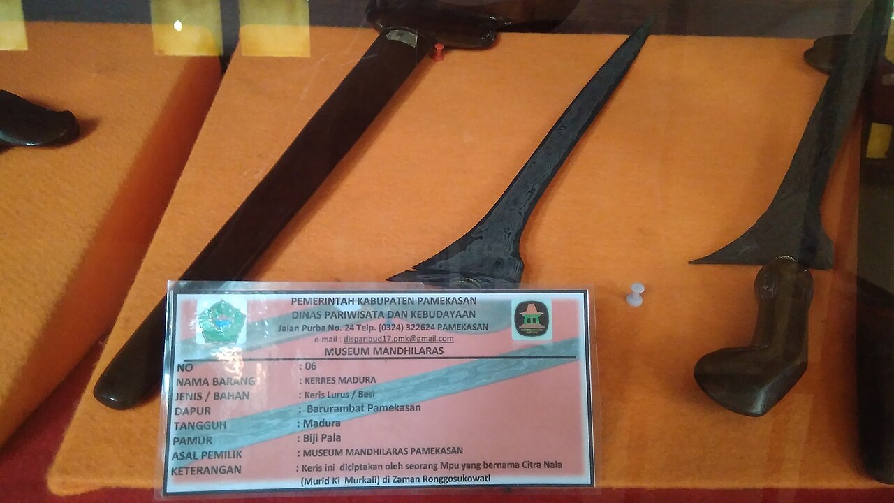 Koleksi bilah keris dengan kartu keterangan di dalam vitrin museum