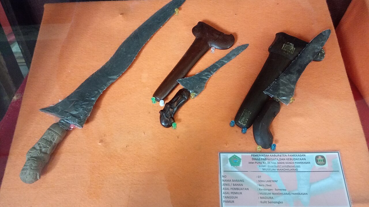 Deretan bilah keris berpamor dipajang mendatar di dalam lemari kaca museum