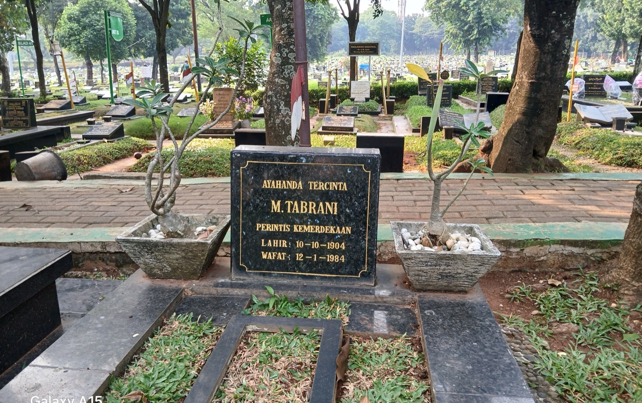 Nisan hitam bertulisan emas M. Tabrani, Perintis Kemerdekaan, lahir 10-10-1904, wafat 12-1-1984, diapit dua pot tanaman di pemakaman yang rindang