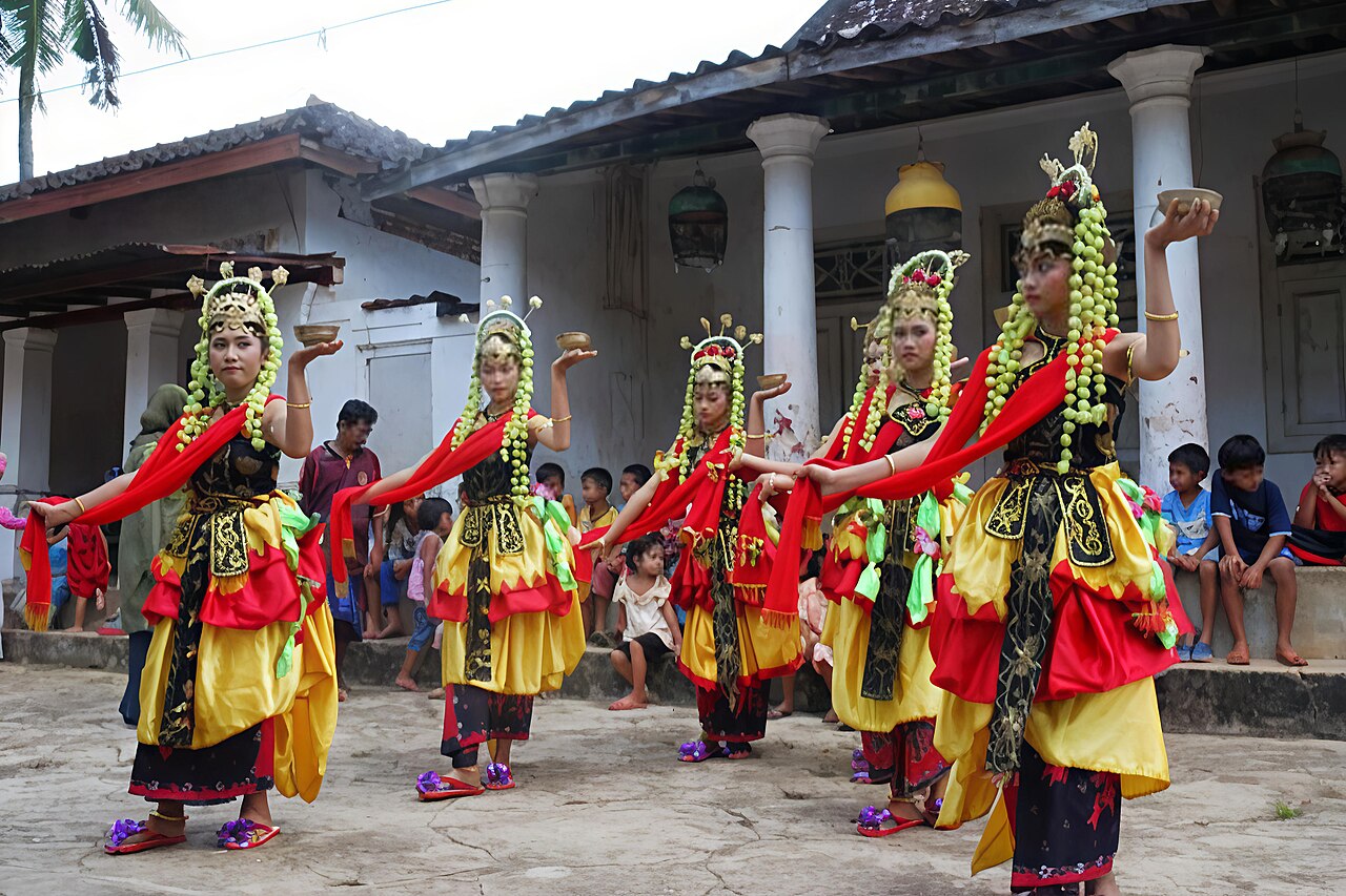 Sekelompok penari Muang Sangkal berkostum merah kuning menari berjajar di halaman