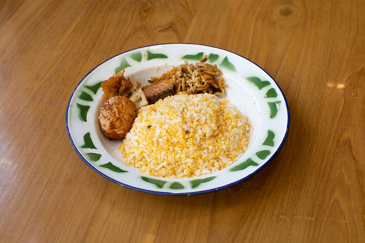 Sepiring nasi jagung kuning di piring seng dengan lauk di sisinya