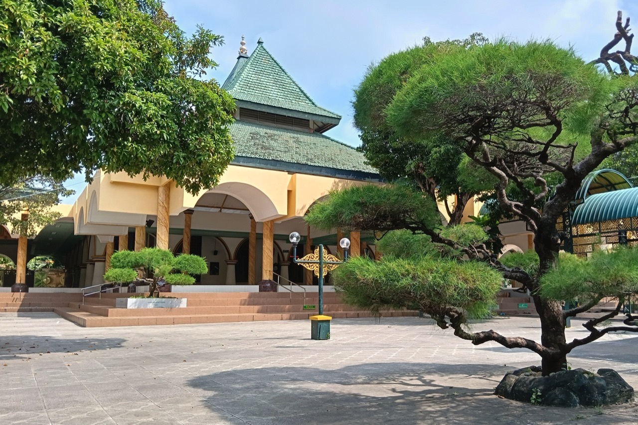 Masjid Jamik Sumenep dengan atap tumpang bersusun dan pohon cemara tua di halamannya