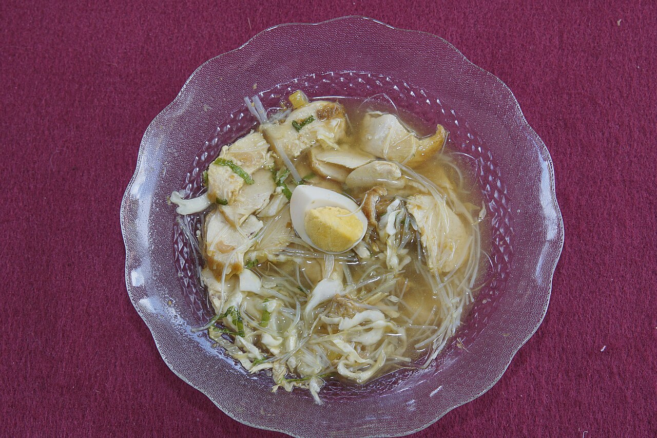 Semangkuk soto Madura berkuah cokelat dengan irisan daging dan taburan bawang goreng