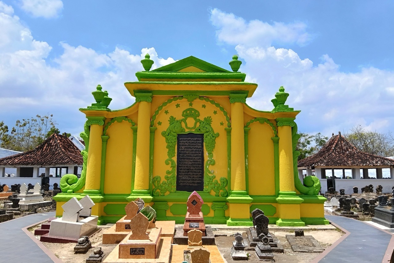 Bangunan makam berkubah dengan dinding kuning dan ukiran hijau di kompleks Asta Tinggi, dikelilingi nisan-nisan
