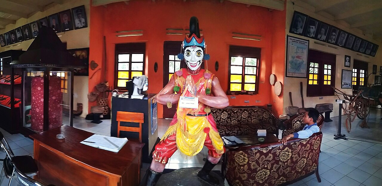 Patung penari topeng ghettak berkostum merah dan kuning di ruang pamer museum