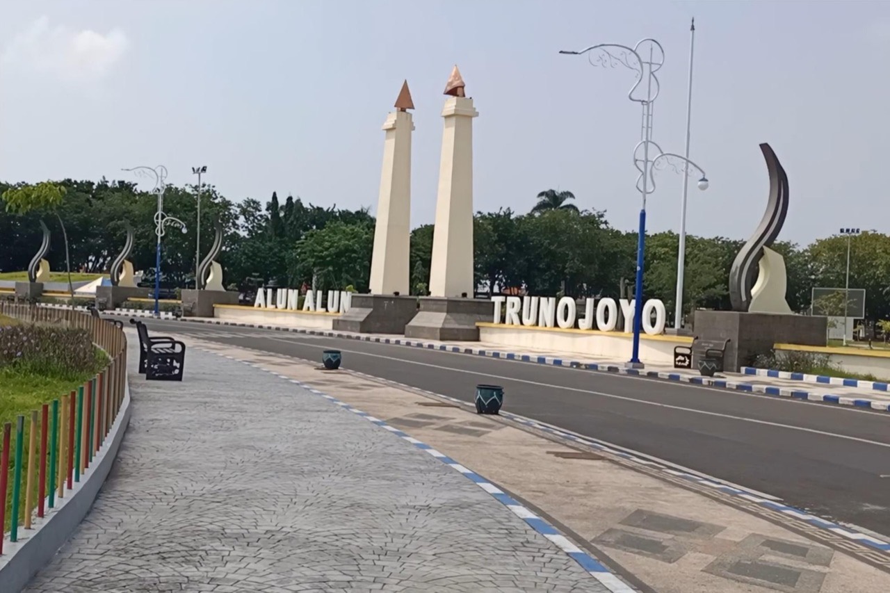 Gerbang bertuliskan Alun-Alun Trunojoyo di Sampang, dua tugu putih mengapit jalan masuk