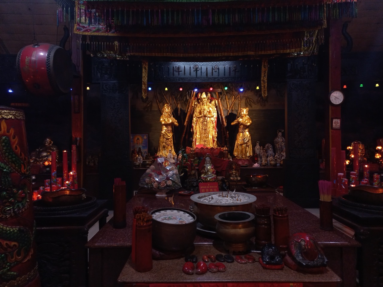 Altar utama vihara dengan tiga arca berlapis emas, tempat dupa dari kuningan, dan bedug merah di sisi kiri